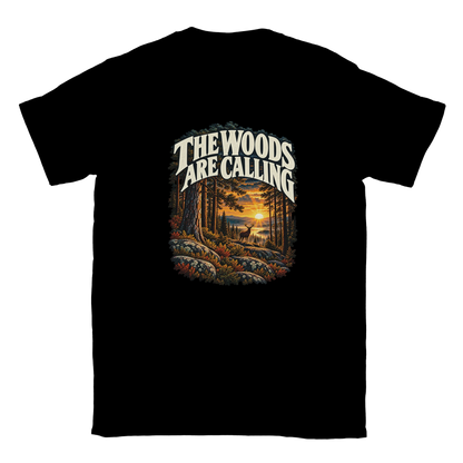 The Woods Are Calling - T-shirt in Black. A deer between tall pine trees in golden light beneath The Woods Are Calling lettering.