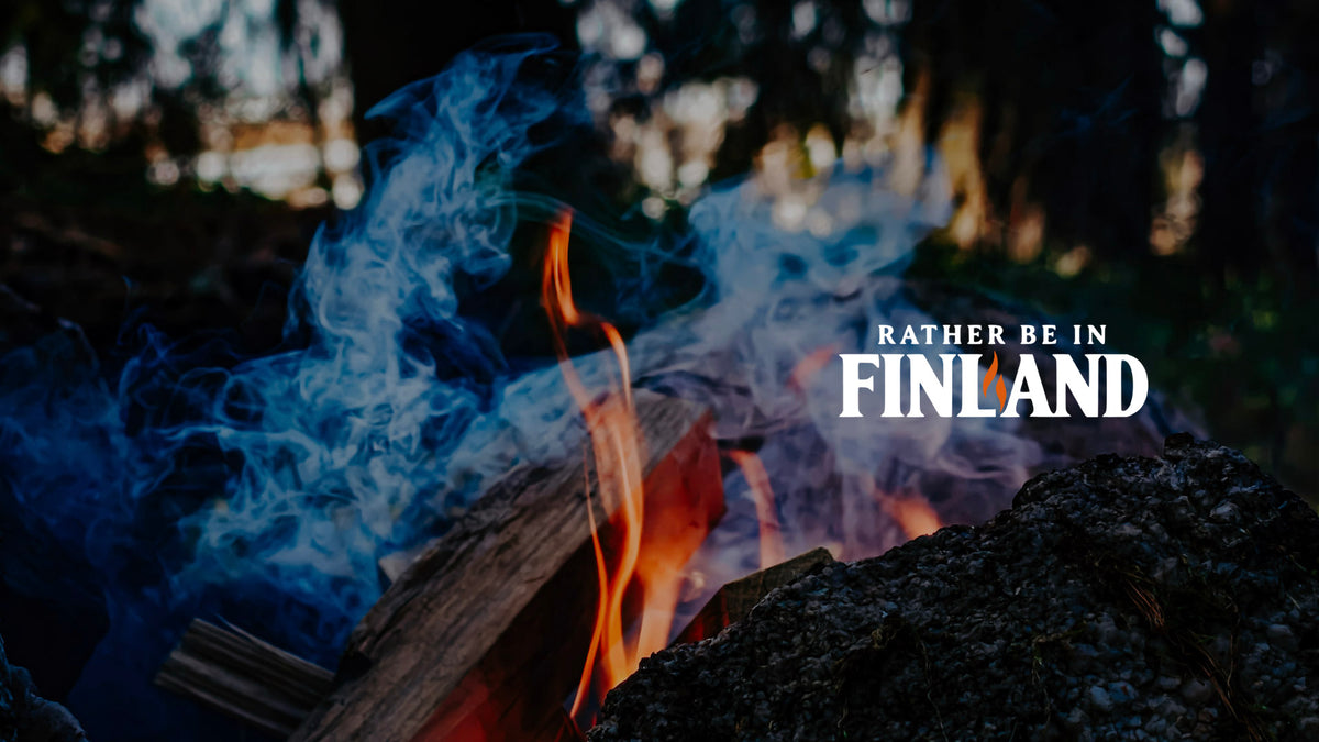 Campfire and drifting smoke in a Finnish forest, with the Rather Be In Finland logo